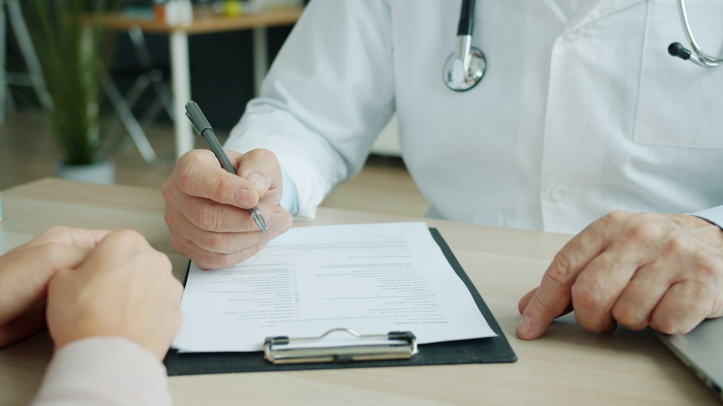 Medico scrive su un blocco note durante una visita.