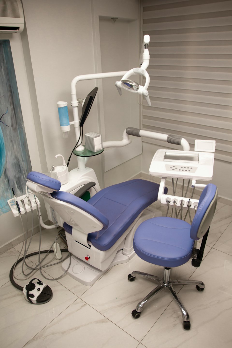 Moderna sala di esame dentistico con sedia blu e bianca.