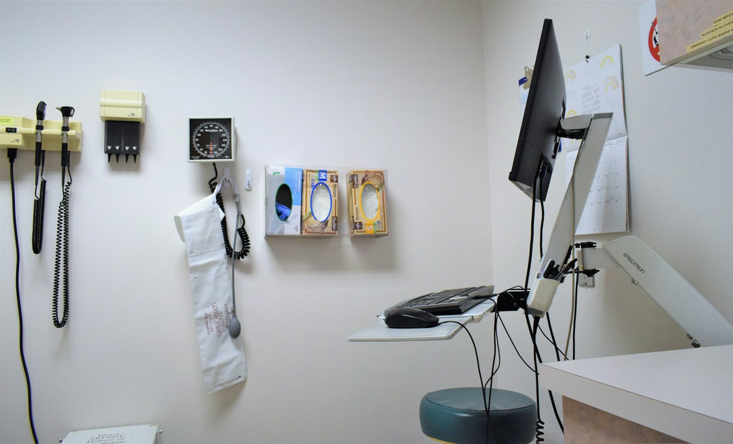 Sala d'esame medico con attrezzature mediche e computer.